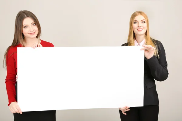 Two business women with blank form on grey background — Stock Photo, Image