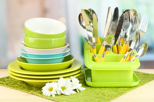 Placas, garfos, facas, colheres e outros utensílios de cozinha em guardanapo de cor, no fundo brilhante — Fotografia de Stock