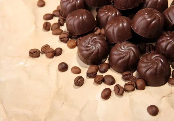 Chocolade snoepjes en koffie bonen, op beige papier achtergrond — Stockfoto