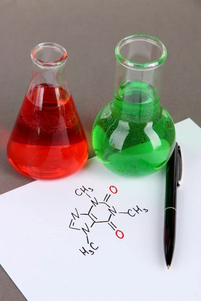 Тестовые трубки с красочными жидкостями и формулами на сером фоне — стоковое фото