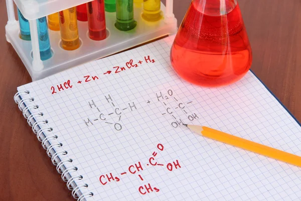 A táblázatban képletek és színes folyadékok kémcsövek — Stock Fotó