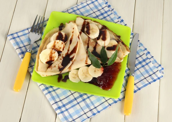 Pancakes con banana su piatto su sfondo di legno — Foto Stock