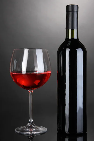 Verre à vin rouge et bouteille de vin sur fond gris — Photo