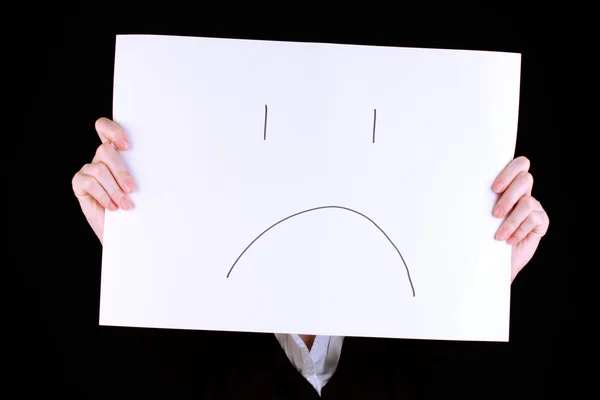 Woman holding paper with sad emoticon, isolated on black — Stock Photo, Image