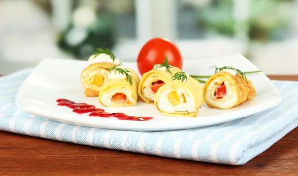 Rotoli d'uovo con crema di formaggio e paprika, su piatto, su sfondo brillante — Foto Stock