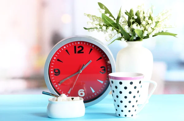 Cup tea and clock on bright background — Stock Photo, Image