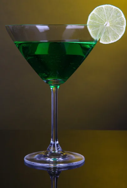 Green cocktail in martini glass on dark yellow background — Stock Photo, Image