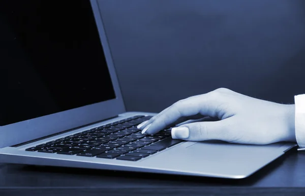 Manos femeninas escribiendo en laptot en luz azul de cerca — Foto de Stock