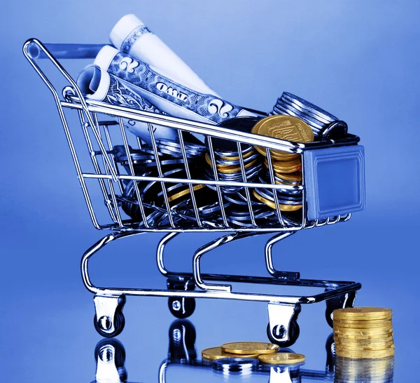 Geld in winkelwagen in blauw licht — Stockfoto