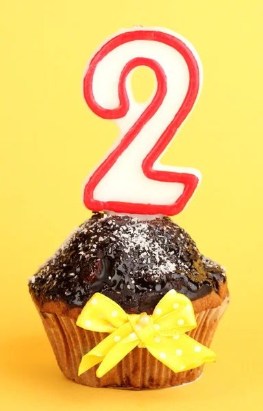 Cupcake di compleanno con glassa al cioccolato su sfondo giallo — Foto Stock