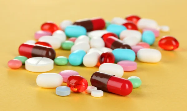 Assortment of pills, tablets and capsules on yellow background — Stock Photo, Image