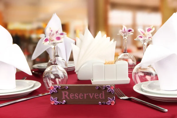 Reserved sign on restaurant table with empty dishes and glasses — Stock Photo, Image