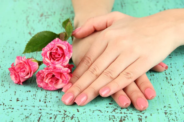 ピンクのマニキュアと色の背景上の花を持つ女性手 — ストック写真