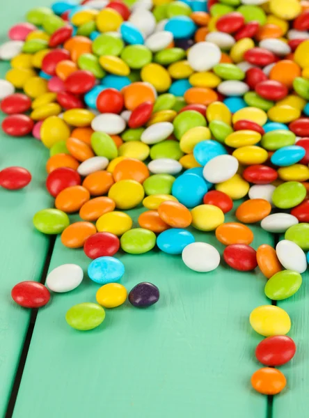 Kolorowe cukierki na zielonym tle drewniane — Zdjęcie stockowe
