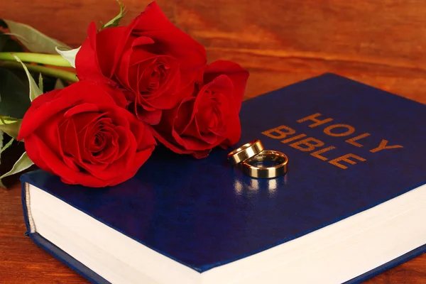 Anillos de boda en la biblia con rosas sobre fondo de madera — Foto de Stock