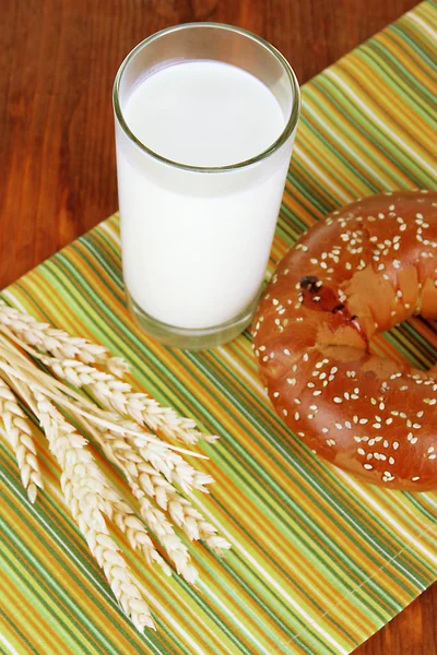 Rouleau de pain et verre de lait sur serviette sur table en bois — Photo