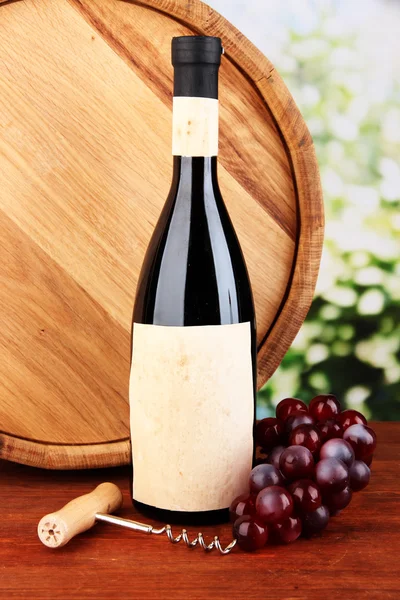 Composition of corkscrew and bottle of wine, grape, wooden barrel on wooden table on bright background — Stock Photo, Image