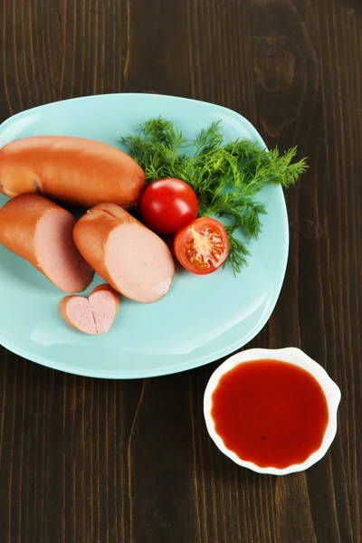 Embutidos, verduras, tomate en plato sobre mesa de madera — Foto de Stock