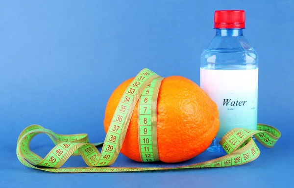 Orange with measuring tape, bottle of water, on color background — Stock Photo, Image