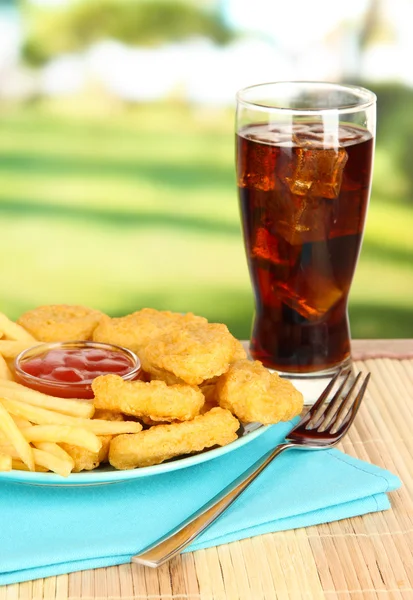 Fried chicken nuggets with french fries,cola and sauce on table in park — Stock Photo, Image