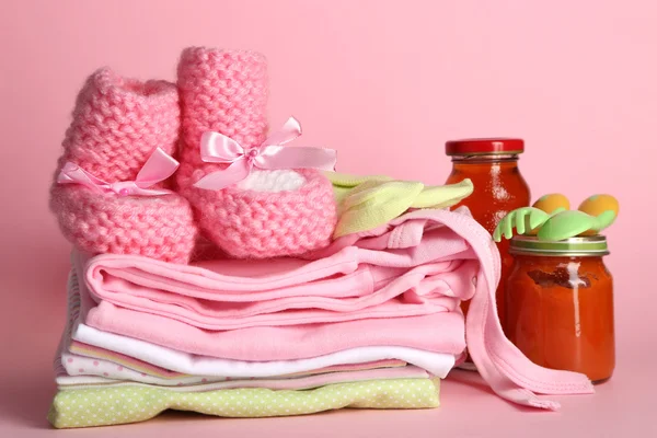 Hög med babykläder på rosa bakgrund — Stockfoto