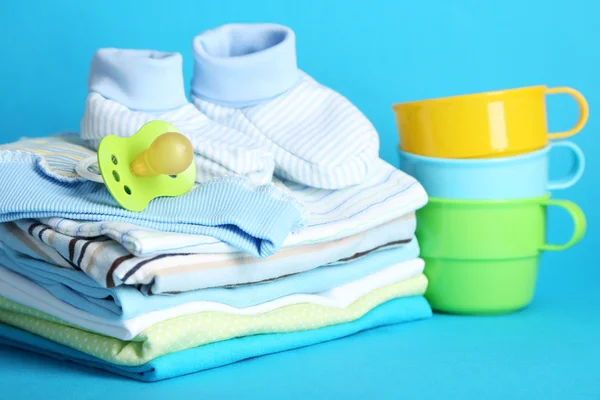 Stapel Babykleidung auf blauem Hintergrund — Stockfoto