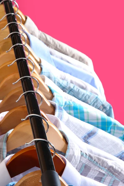 Men's shirts on hangers on pink background — Stock Photo, Image