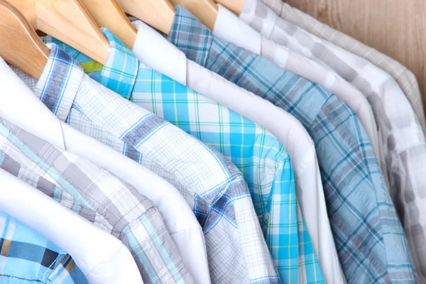Men's shirts on hangers on wooden background — Stock Photo, Image