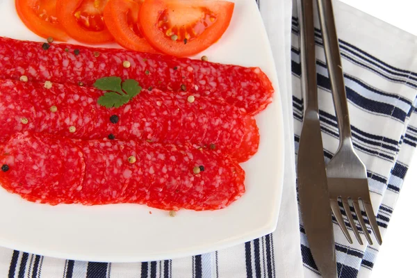 Tasty salami on plate on napkin isolated on white — Stock Photo, Image