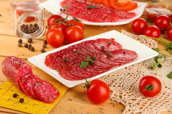 Leckere Salami auf Tellern auf Holztisch in Großaufnahme — Stockfoto