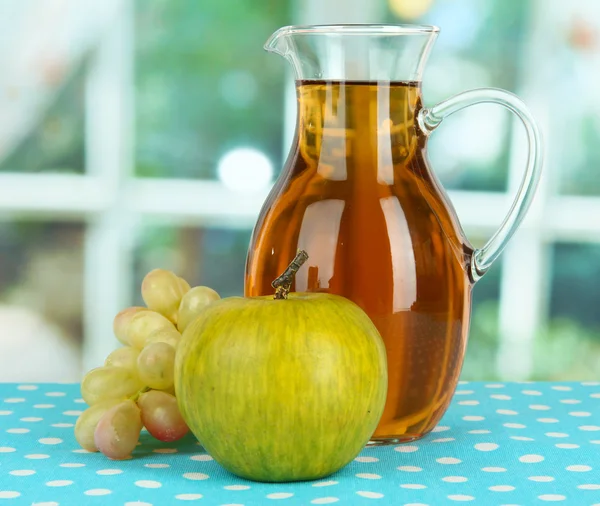 Apple juice in pitcher on table in room — Stock Photo, Image