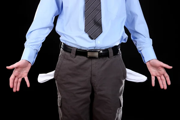Hombre de negocios mostrando sus bolsillos vacíos, sobre fondo negro — Foto de Stock