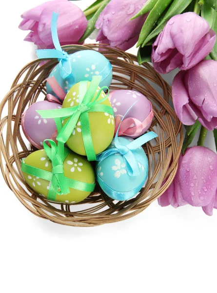 Bright easter eggs in basket and tulips, isolated on white Stock Image
