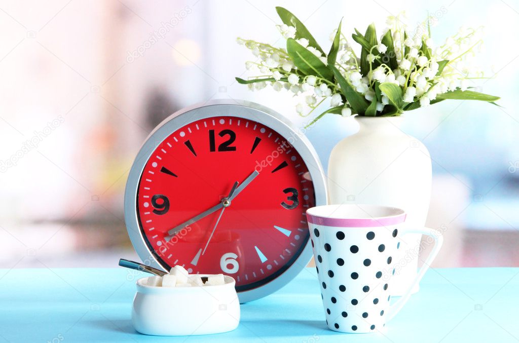 Cup tea and clock on bright background