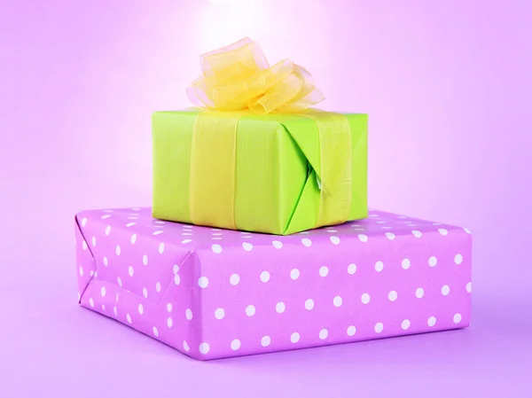 Cadeaux lumineux avec des arcs sur fond violet — Photo