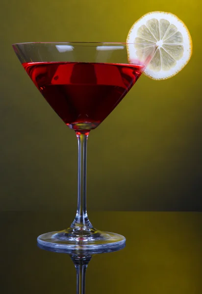 Red cocktail in martini glass on dark yellow background — Stock Photo, Image