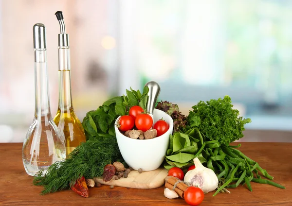 Composition of mortar, bottles with olive oil and vinegar, and green herbals, on bright background — Stock Photo, Image