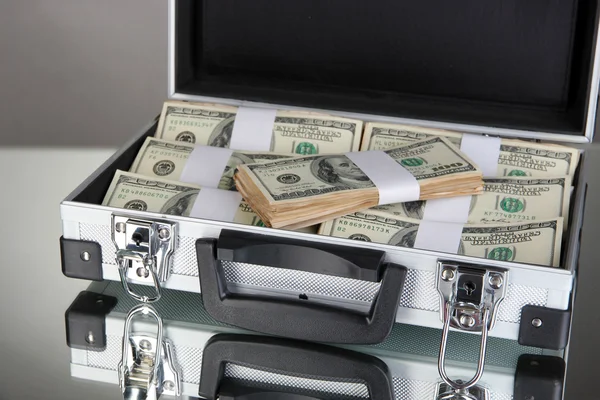 Valise avec billets de 100 dollars sur fond gris — Photo