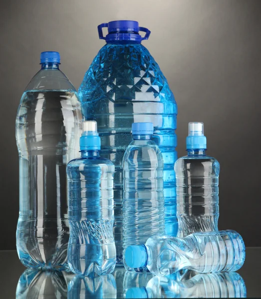 Different water bottles on grey background — Stock Photo, Image