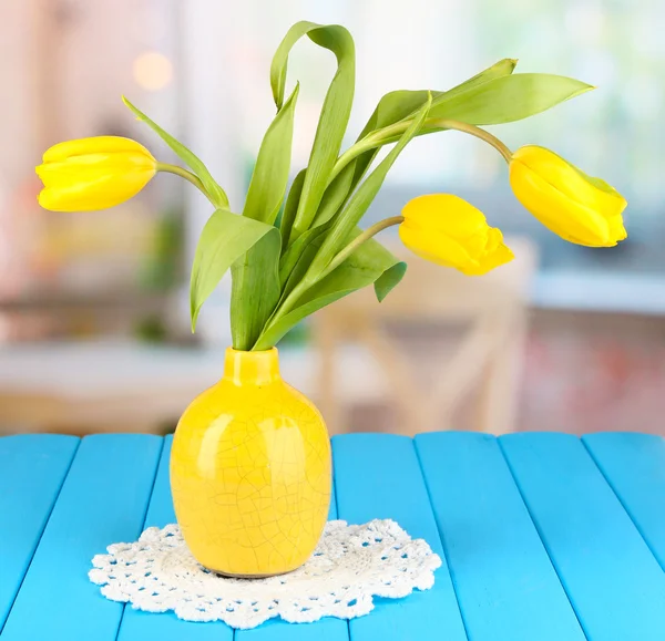 Tulipanes amarillos en jarrón sobre mesa de madera sobre fondo de habitación —  Fotos de Stock