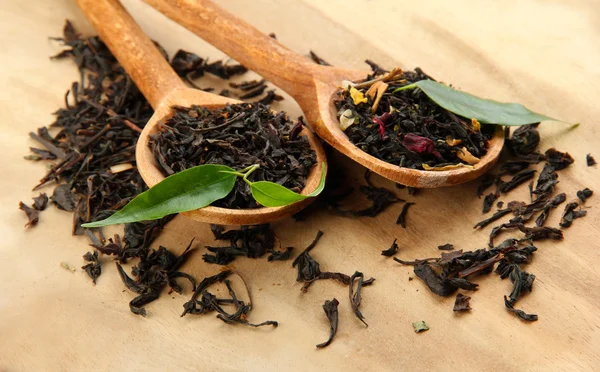 Té seco con hojas verdes en cucharas de madera, sobre fondo de madera —  Fotos de Stock