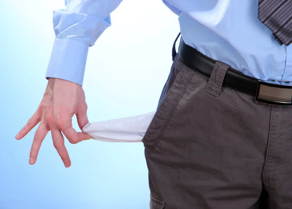 Business man showing his empty pocket, on blue background — Stock Photo, Image
