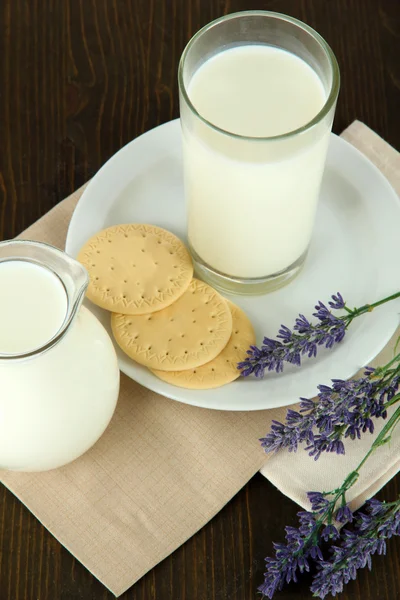 Vetro di latte, una brocca e biscotti su uno sfondo di legno — Foto Stock