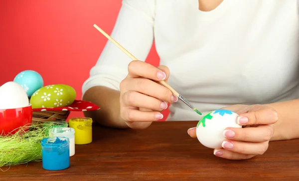 Jovem mulher pintando ovos de Páscoa, no fundo de cor — Fotografia de Stock