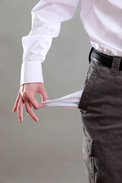 Hombre de negocios mostrando su bolsillo vacío, sobre fondo gris —  Fotos de Stock