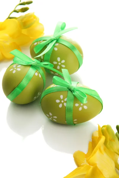 Huevos de Pascua brillantes con lazo y flores, aislados en blanco — Foto de Stock