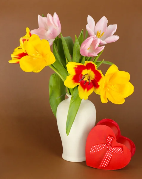 Beautiful tulips in bucket with gift on brown background — Stock Photo, Image