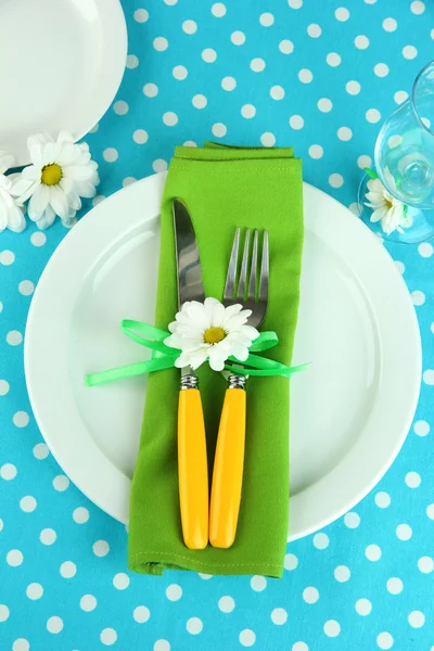 Couteau et fourchette enveloppés dans une serviette, sur une assiette, sur fond de nappe couleur — Photo