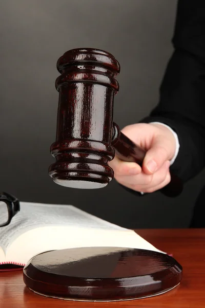 Judge's gavel in hand on grey background — Stock Photo, Image