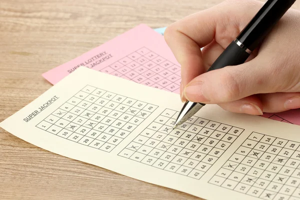 Fechar o bilhete de loteria durante a marcação dos números, em fundo de madeira — Fotografia de Stock